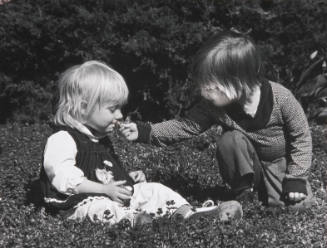 Title unknown (two children smelling flowers outdoors)