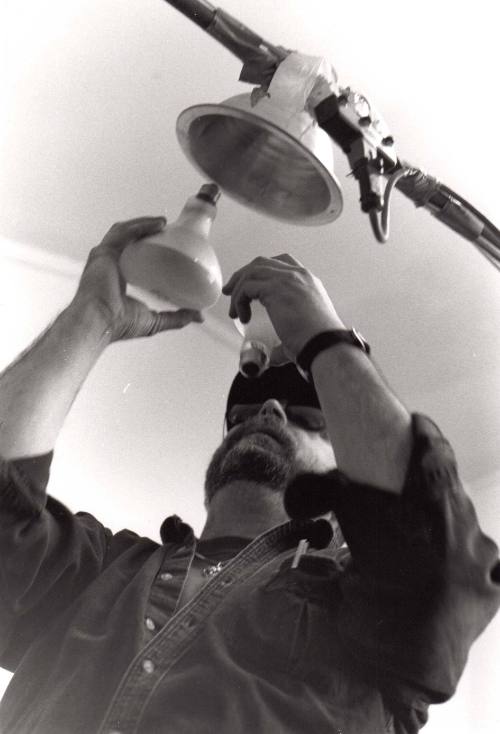 Roger Routson is changing a light bulb in his studio after the graduate students used the lighting system he created in his studio in West Stadium to shot slides of thier work.