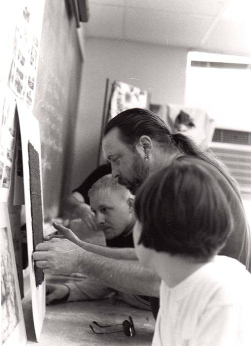 Roger Routson created a paper making assignement for his watercolor class. They are looking at the detail made in the paper by one of the students.