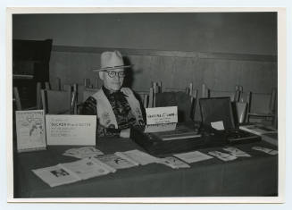 Herschel C. Logan seated at book promotional table