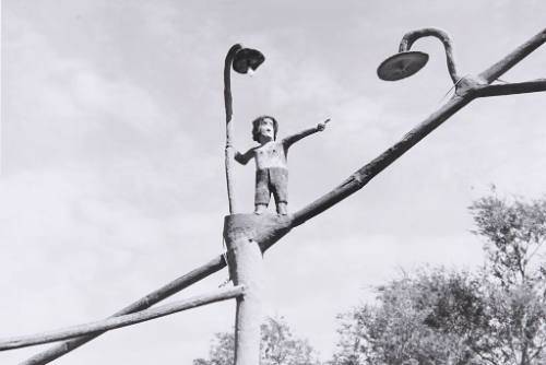 Man in hat pointing toward Goddess of Liberty tree